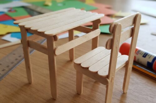 # A Small School Table and Chair Made of Wooden Sticks Making a small school table and chair from wooden sticks is a simple, creative, and educational craft project for children. With a few wooden craft sticks, glue, cardboard, paper, and some imagination, it is possible to create a miniature classroom scene. This project is especially interesting because it transforms simple materials into familiar objects that children see every day at school. The finished table and chair can be used as part of a miniature classroom, dollhouse, school project, or creative display. A miniature school table and chair made from wooden sticks can also introduce children to basic ideas about construction, measurement, balance, design, and organization. While the project looks like a small craft, it requires planning and careful assembly. Children learn that even a simple piece of furniture needs a strong structure to remain stable. ## Understanding the Project A school table and chair are important pieces of classroom furniture. Students use tables for writing, reading, drawing, and completing school activities. Chairs allow them to sit comfortably while learning. Creating miniature versions of these objects gives children an opportunity to understand how furniture is constructed. Wooden craft sticks are especially useful because they are lightweight, easy to arrange, and strong enough for small models. The project can be adapted to different ages. Younger children can make a basic table and chair with adult assistance, while older children can create more detailed models with tabletops, legs, backrests, shelves, and decorations. The finished furniture does not need to be perfectly realistic. The main purpose is to encourage creativity and teach children how different pieces can be joined together to create a stable structure. ## Materials Needed The main material for the project is wooden craft sticks. These can be ordinary flat wooden sticks or slightly thicker craft sticks. The number needed depends on the size and design of the model. Other materials include strong craft glue, cardboard, a ruler, a pencil, scissors, paper, markers, and paint. Cardboard can be used as a base to make the furniture more stable. Small pieces of ribbon, colored paper, stickers, or foam can be used for decoration. If children want to create a complete miniature classroom, additional materials can include bottle caps, cardboard boxes, paper, and recycled packaging. It is useful to prepare all materials before construction begins. Keeping everything nearby makes the activity easier and more organized. ## Planning the Design Planning is an important part of building miniature furniture. Before gluing the wooden sticks together, children should decide how the table and chair will look. A simple drawing can show the tabletop, legs, and supports. Another drawing can show the chair seat, legs, and backrest. The proportions should be considered carefully. The chair should be smaller than the table, and the table should be wide enough to look comfortable for a miniature student. Using a ruler helps children create pieces that are similar in length. Accurate measurements can make the final model more balanced. ## Making the Tabletop The tabletop is usually the first part of the miniature table to build. Several wooden sticks can be placed next to each other horizontally to form a flat surface. Small wooden sticks can be glued across the underside as supports. These supports hold the main sticks together and prevent them from moving apart. The tabletop should be allowed to dry before the legs are attached. If the glue is still wet, the sticks may move out of position. For a different design, cardboard can be used as the tabletop and covered with wooden sticks. This can provide additional strength and make construction easier. ## Building the Table Legs The legs are responsible for supporting the tabletop. Four wooden sticks can be used as legs, one near each corner. The sticks should be attached vertically or at a slight angle, depending on the desired design. It is important to make sure that the legs are approximately the same length. Unequal legs can cause the table to wobble. Small horizontal supports can be added between the legs. These supports strengthen the structure and make the miniature table more realistic. The table should be placed on a flat surface during construction so that the legs can be adjusted before the glue dries. ## Adding Table Supports Real tables often contain supporting structures beneath the tabletop. A miniature table can include small wooden sticks connecting the legs. These supports can form a rectangle underneath the tabletop. They make the model stronger and demonstrate how structural support works. Children can observe that a table is not simply a flat surface with legs. Different parts work together to distribute weight and keep the furniture stable. This is a simple introduction to engineering concepts. ## Making the Chair Seat The chair can be made in a similar way. Several wooden sticks can be arranged side by side to create the seat. Two or more sticks can be placed underneath as supports. The seat should be smaller than the tabletop. Its size should also match the height of the miniature table. A cardboard seat can be used if children find it difficult to connect many wooden sticks. Wooden sticks can then be placed over the cardboard to create a natural wooden appearance. ## Building the Chair Legs Four wooden sticks can form the chair legs. They should be attached underneath the seat. The legs must be positioned carefully so that the chair can stand without falling. Additional horizontal supports can be placed between the legs. These supports make the chair stronger and can also give it a more realistic appearance. Children should test the chair on a flat surface before continuing. If it leans to one side, one of the legs may need to be repositioned. ## Creating the Chair Backrest A school chair usually has a backrest, and adding one makes the miniature model look more complete. Several wooden sticks can be placed vertically or horizontally to create the backrest. Two longer sticks can serve as side supports. The backrest should be attached securely to the back of the seat. Children can experiment with different patterns. For example, they can create a simple solid backrest or arrange the sticks in a decorative pattern. ## Decorating the Furniture Once the table and chair are structurally complete, children can decorate them. The wooden sticks can be left natural for a simple wooden appearance. They can also be painted in bright colors. A school table might be painted blue, green, yellow, or another favorite color. The chair can match the table or have a contrasting color. Small drawings or patterns can be added using markers. Children can also place a tiny paper book, pencil, or notebook on the table. Decorations should be added after the glue has completely dried. ## Creating a Miniature Classroom The small table and chair can become part of a larger classroom model. A cardboard box can serve as the classroom walls. Children can create several tables and chairs for miniature students. A teacher's desk, blackboard, bookshelf, classroom door, and windows can also be added. A small piece of black or dark-colored cardboard can become a chalkboard. Tiny pieces of paper can represent books and classroom posters. This larger project allows children to imagine what happens inside a classroom and how different objects are organized. ## Adding Miniature Students Tiny students can be made from paper, cardboard, modeling clay, or other craft materials. They can be placed on the chairs around the tables. Some can appear to be writing, while others can be reading or raising their hands. Adding students makes the classroom scene more lively. Children can also create a miniature teacher and place the figure near the teacher's desk. This can lead to storytelling activities in which children imagine a lesson taking place inside their handmade classroom. ## Educational Benefits The wooden-stick school furniture project provides many educational benefits. It develops creativity because children must imagine how simple sticks can become recognizable objects. It also improves fine motor skills. Picking up small sticks, applying glue, positioning pieces, and decorating the furniture require careful hand movements. The activity develops patience as well. Glue needs time to dry, and some parts may need to be adjusted before the model is finished. Children also practice problem-solving. If the table is unstable, they need to determine why and find a solution. ## Learning About Measurement The project provides a natural way to practice measurement. Children can measure the lengths of wooden sticks and compare the sizes of the table and chair. They can learn about concepts such as height, width, length, symmetry, and proportion. For older students, the project can become a simple mathematics activity. They might calculate how many sticks are needed or determine the difference between the height of the table and chair. This demonstrates how mathematics can be used in practical situations. ## Learning About Balance and Structure The project also introduces basic engineering concepts. A table must have a stable base, and its legs need to be positioned correctly. The same principle applies to the chair. If one leg is too short or poorly positioned, the chair may wobble. Children can experiment with different structures and observe which designs are stronger. This type of hands-on learning helps children understand that objects are designed according to practical principles. ## Using Recycled Materials Although wooden craft sticks are the main material, many other parts of the project can be made from recycled items. Old cardboard can become a classroom floor. Packaging can become walls, shelves, or books. Paper scraps can become posters and notebooks. Using recycled materials teaches children that useful craft supplies can often be found around the home. It also encourages environmental responsibility by showing that materials can be reused creatively. ## Working as a Group The project can be completed individually or as a group activity. In a classroom, students can work together to create a complete miniature school. One group can build tables and chairs, another can create the classroom walls, and another can make books, students, and decorations. Working together encourages communication and cooperation. Each student can contribute a different skill, making the final project a shared achievement. ## Common Challenges One common challenge is keeping the wooden sticks in place while the glue dries. Children can use small pieces of tape to temporarily hold them together. Another challenge is creating equal-length legs. Measuring the sticks before construction helps solve this problem. The table or chair may also become too heavy if too much glue or too many materials are used. Using only the necessary amount of material keeps the model light. If the furniture becomes unstable, extra supports can be added underneath. These challenges are valuable because they encourage children to experiment and improve their designs. ## Safety Tips Children should use scissors and craft materials carefully. Young children may need adult assistance when cutting cardboard or using certain types of glue. Glue should be used in a well-ventilated area and according to its instructions. Hot glue guns should only be handled by adults or used under close adult supervision. Wooden sticks should be checked to ensure that they are smooth and free from sharp splinters. A clean work surface makes the project safer and easier to manage. ## Conclusion A small school table and chair made from wooden sticks is a wonderful craft project that combines creativity, education, and simple construction. With a few wooden sticks, glue, cardboard, and decorative materials, children can create miniature furniture that resembles the tables and chairs found in a real classroom. The activity teaches much more than crafting. Children learn about measurement, balance, structure, proportion, organization, and problem-solving. They also develop fine motor skills and patience as they carefully position and glue each piece. The finished table and chair can stand alone as a miniature display or become part of a larger school model. Children can add a blackboard, teacher's desk, books, students, shelves, and other classroom objects to create a complete miniature learning environment. Perhaps the most valuable lesson is that simple materials can be transformed through creativity. A collection of ordinary wooden sticks can become useful-looking furniture when the pieces are carefully planned and assembled. This encourages children to look at everyday materials in new ways. Whether made at home, in a classroom, or as part of a school exhibition, a wooden-stick school table and chair provide an enjoyable hands-on experience. The project combines art with practical learning and gives children the satisfaction of creating something with their own hands. In the end, the tiny table and chair are not only attractive handmade objects but also examples of creativity, patience, teamwork, and simple engineering.