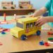 # How to Make a School Bus That Moves Using Cardboard Making a school bus that moves using cardboard is a fun, creative, and educational project for children. It combines arts and crafts with simple mechanical ideas, allowing students to build a small model vehicle from materials that are easy to find at home or in the classroom. The project can be made from an old cardboard box, paper, bottle caps, wooden sticks, glue, and other recycled materials. With a little imagination, an ordinary piece of cardboard can become a colorful school bus with wheels that actually move. This project is especially interesting because it is not only about decoration. A moving cardboard school bus introduces children to basic ideas about wheels, axles, balance, movement, and design. Children can learn how vehicles work while enjoying a hands-on activity. They can also customize their bus with windows, doors, seats, lights, a driver, and a school name. ## Understanding the Project A cardboard school bus is a miniature model of a real school transportation vehicle. The basic structure can be made from thick cardboard, while the wheels can be made from bottle caps, cardboard circles, or other round recycled materials. To make the bus move, the wheels need to be attached to axles that can rotate freely. The simplest design uses two axles passing underneath the body of the bus. Each axle connects two wheels. When the wheels turn, the bus can roll forward or backward. Children can make the bus move by pushing it gently with their hands. Older students can also explore simple mechanical methods, such as using a rubber-band mechanism or a small low-voltage motor under adult supervision. However, a hand-pushed model is often the easiest and safest version for younger children. ## Materials Needed The materials for this project are inexpensive and easy to find. The main material is strong cardboard. An old delivery box, cereal box, or packaging box can be reused for the bus body. Other useful materials include colored paper, scissors, glue, tape, a ruler, a pencil, markers, and crayons. Bottle caps can make excellent wheels because they are already round and strong. Alternatively, children can cut circles from cardboard. For the axles, straight wooden sticks, paper tubes, or sturdy straws can be used depending on the size of the model. Drinking straws can act as small axle holders, allowing the axle to rotate more easily. Additional decorations may include black paper, white paper, stickers, small pieces of foam, yarn, buttons, and recycled packaging materials. ## Planning the School Bus Before cutting the cardboard, it is helpful to make a simple plan. Children should decide how large the bus will be and where the wheels, windows, doors, and other parts will go. A rectangular shape works well for the main body. The front can be slightly rounded or slanted to make the bus look more realistic. The roof can remain flat, or another piece of cardboard can be shaped to create a curved appearance. The size of the wheels should also be considered during planning. If the wheels are too small, they may not support the bus properly. If they are too large, they can interfere with the body. Drawing the design first makes construction easier and reduces wasted cardboard. ## Building the Bus Body The bus body can be made from several pieces of cardboard. A large rectangular piece can form the main body, while smaller pieces can create the front, back, roof, and sides. A simple method is to cut one long piece with folding lines. The cardboard can then be folded into a box-like shape. Another method is to cut each wall separately and glue them together. The edges should be secured with strong tape or glue. Children should allow the glue to dry before adding heavy decorations. The body should be strong but not too heavy. A very heavy bus may make the wheels difficult to turn. ## Creating the Windows Windows give the cardboard school bus its recognizable appearance. Several rectangular windows can be drawn along both sides. Children can cut out the windows completely or simply draw them using a dark marker. If they want a more detailed model, transparent plastic from clean packaging can be attached behind the openings. Each window can contain a small paper passenger. This creates the appearance of children sitting inside the bus. The front windshield can be made slightly larger than the side windows. A rear window can also be added. ## Making the Wheels The wheels are one of the most important parts of the moving bus. Four wheels are enough for a simple model, although larger models can use six wheels. Bottle caps are a convenient choice because they are already circular. If bottle caps are unavailable, students can draw circles on cardboard using a cup or another round object as a guide. The circles can then be carefully cut out. The wheels should be approximately the same size. This helps the bus remain balanced. The wheels can be decorated with black paper or markers. Small white circles in the center can represent hubcaps. ## Creating the Axles The axles allow the wheels to rotate. Two straight sticks can be used, one for the front wheels and one for the rear wheels. Small pieces of drinking straw can be attached underneath the cardboard body. The axle is then passed through the straw. Because the straw is smooth inside, the axle can rotate more easily. The wheels are attached to the ends of the axle. They should be fixed securely but in a way that still allows the axle to rotate. This part of the project introduces an important mechanical idea an axle supports the wheels and allows them to turn together. ## Testing the Movement Once the wheels are attached, the bus should be tested before adding too many decorations. Place it on a smooth, flat surface and gently push it. If it moves forward smoothly, the basic mechanism is working correctly. If it turns to one side, one wheel or axle may not be aligned properly. If the wheels do not turn, the axle may be stuck against the cardboard. The holes may need to be adjusted, or the straw supports may need to be repositioned. Testing early is important because mechanical problems are easier to fix before the model becomes heavily decorated. ## Adding the School Bus Colors After the structure and wheels work properly, children can decorate the bus. Traditional school buses are often yellow, making yellow paper or paint a natural choice. However, children can create their own colorful designs. They might use blue, green, orange, or another color. The important thing is that the bus should be easy to recognize. A black strip along the side can make the model look more realistic. Black lines can also separate the windows. A school name can be written on the side. Children might invent a name such as “Happy School Bus” or use the name of their school. ## Adding Doors and Lights A small door can be drawn near the front or side of the bus. It can be made from cardboard and attached with tape so that it opens and closes. Headlights can be represented with small white or yellow circles. Red circles at the back can represent rear lights. A stop sign can also be added to the side of the bus. These small details help children understand the different safety features found on real vehicles. ## Creating a Miniature Driver and Passengers The bus becomes more interesting when it has people inside. Children can draw small passengers on paper and cut them out. The driver can sit at the front behind the windshield. Several children can be placed behind the driver. For a three-dimensional effect, tiny cardboard seats can be made inside the bus. If the side windows are open, viewers can see the passengers sitting inside. This part of the project can also encourage storytelling. Children can imagine where the bus is going and create a story about the students traveling to school. ## Making the Bus Move in Different Ways The simplest moving cardboard school bus is pushed by hand. This is ideal for younger children and requires no complicated equipment. Another possibility is a rubber-band-powered mechanism. A rubber band can store energy when it is twisted and can release that energy to turn an axle. This design requires careful construction and adult assistance. Older students can experiment with a small battery-powered motor designed for educational projects. A motor can turn the wheels and make the bus move without being pushed. When using batteries, wires, motors, or electrical components, children should work with an adult and use only safe, low-voltage educational equipment. ## Learning Through the Project The moving cardboard school bus is more than a craft. It can become a simple science and engineering lesson. Children learn that wheels reduce friction and make transportation easier. They discover that an axle connects wheels and helps them rotate. They also learn that balance and alignment are important when building a moving object. The project introduces children to engineering design. They make a plan, build a model, test it, identify problems, make changes, and test it again. This process teaches an important lesson mistakes are part of learning. If the first version does not move correctly, children can investigate the problem and improve the design. ## Environmental Benefits of Cardboard Crafts Using cardboard for the school bus also encourages recycling. Instead of throwing away packaging, children can reuse it as a building material. This teaches an important environmental message. Many household objects can have a second life when people use creativity and imagination. Reusing cardboard also makes the project inexpensive. Families and schools do not need to purchase special construction materials. The activity can therefore combine creativity, science, and environmental education in one project. ## Turning the Project Into a Classroom Activity Teachers can turn the cardboard bus into a larger classroom challenge. Students can work individually or in small groups to create different buses. Each group can test how far its bus travels when pushed with the same amount of force. Students can measure the distance and compare the results. They can also experiment with different wheel sizes, axle positions, and bus weights. This turns a simple craft into an introduction to scientific observation and fair testing. Students can record their results and discuss why some designs moved farther than others. ## Safety During Construction Safety should always be considered when making cardboard crafts. Scissors should be used carefully, and younger children may need adult assistance when cutting thick cardboard. Hot glue guns should only be used by adults or under close adult supervision. Children should also avoid sharp tools and unsafe electrical components. The work area should be clean and organized. Small pieces of cardboard, glue, and other materials should be removed when the project is finished. ## Conclusion A school bus that moves using cardboard is an exciting project that brings together creativity, recycling, science, and simple engineering. Starting with an ordinary piece of cardboard, children can create a miniature vehicle with a body, windows, wheels, axles, seats, passengers, and decorations. The moving feature makes the project especially enjoyable because children can test their creation instead of simply looking at it. They can push the bus across a table, observe how the wheels turn, identify problems, and improve the design. The project also teaches valuable skills. Children practice measuring, cutting, folding, gluing, decorating, planning, and problem-solving. They learn that successful construction requires patience and testing. Most importantly, they discover that science and creativity can work together. A cardboard school bus can become much more than a small toy. It can be a classroom science experiment, an art project, a recycling activity, or a demonstration of basic mechanical principles. With simple materials and a little imagination, children can transform recycled cardboard into a fun moving vehicle while learning important lessons about design, motion, teamwork, and responsible use of materials.